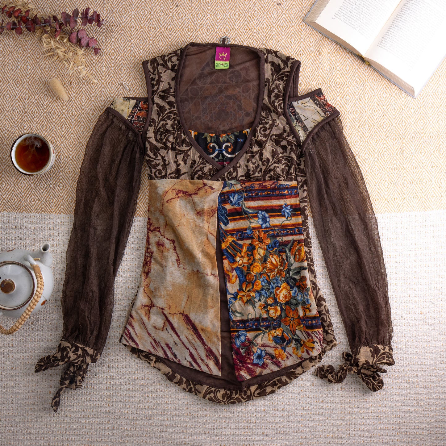 Vintage Save the Queen Y2K Sheer Mesh Tunic Top – dark chocolate brown sheer mesh with tonal baroque damask print, cold shoulder cut-out with zip detail, long bishop sleeves with self-tie cuffs, patchwork front panel combining marble print and blue floral tapestry fabric, fairy grunge maximalist aesthetic, Save the Queen label, flat lay editorial shot