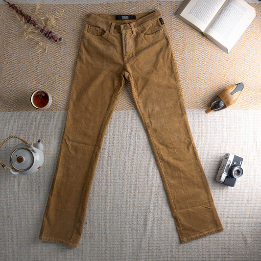 Vintage Versace Jeans Couture Deadstock 90s Camel Corduroy Trousers – warm camel tan fine-wale corduroy with gold glitter shimmer, high waist, five-pocket straight leg fit, gold Medusa hardware button, Versace Jeans Couture label at waistband, flat lay editorial shot