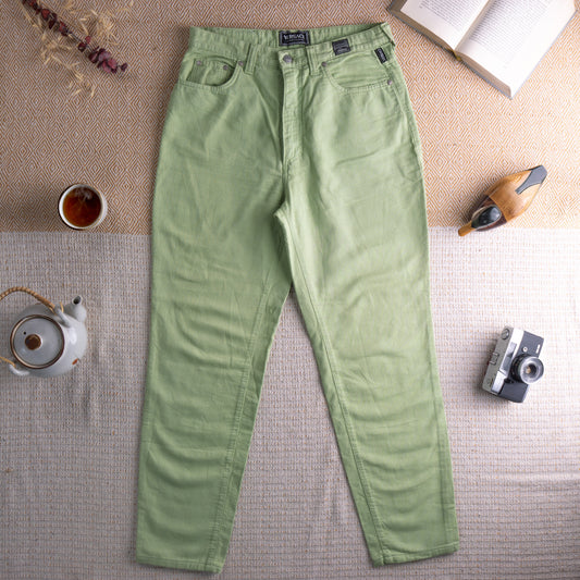 Vintage Versace Jeans Couture 90s Lime Green Trousers – sage lime green textured cotton, high waist, five-pocket mom fit, silver Medusa logo button, straight leg silhouette, Versace Jeans Couture label at waistband, flat lay editorial shot