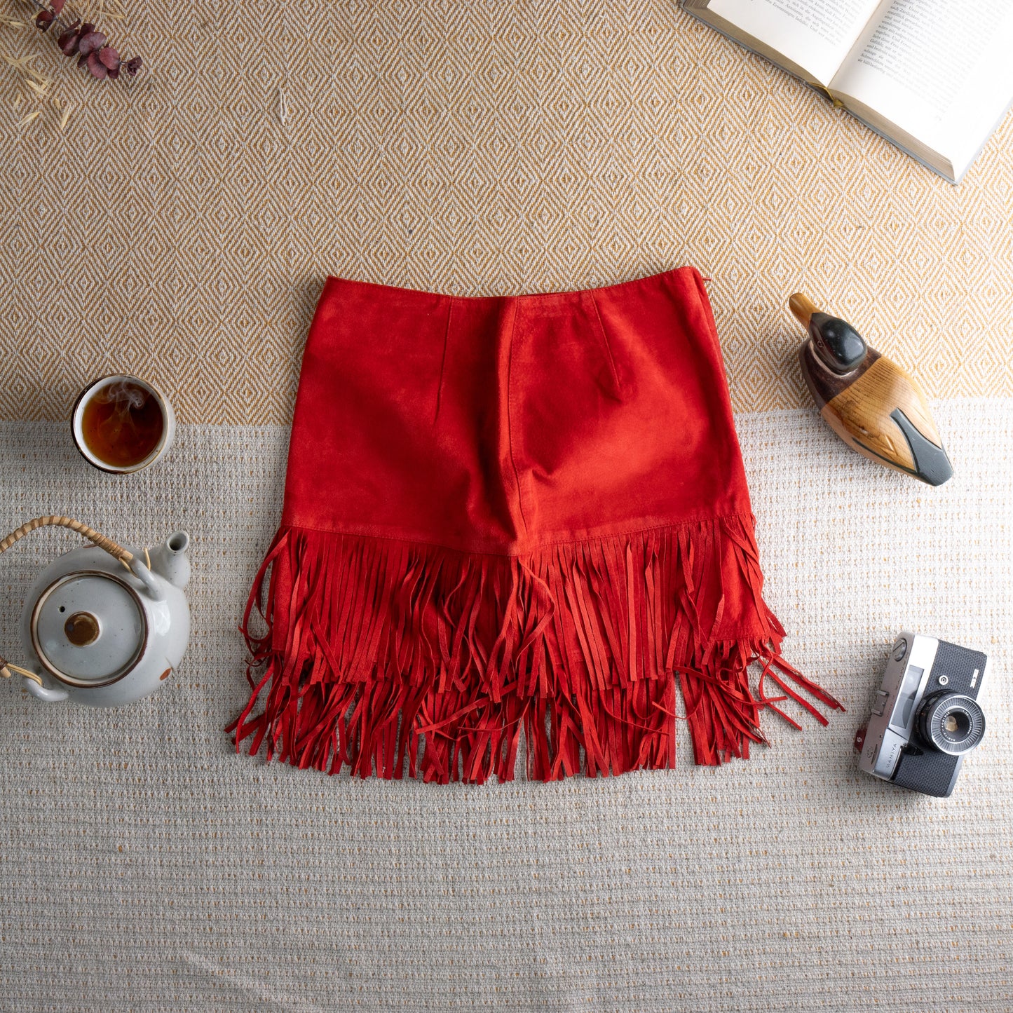 back view Vintage Blumarine Folies Y2K Red Suede Fringe Mini Skirt – vibrant red genuine leather suede, high waist, A-line silhouette with dramatic double-layer fringe hem, rhinestone crystal "B" logo detail at hip, western glam aesthetic, flat lay editorial shot