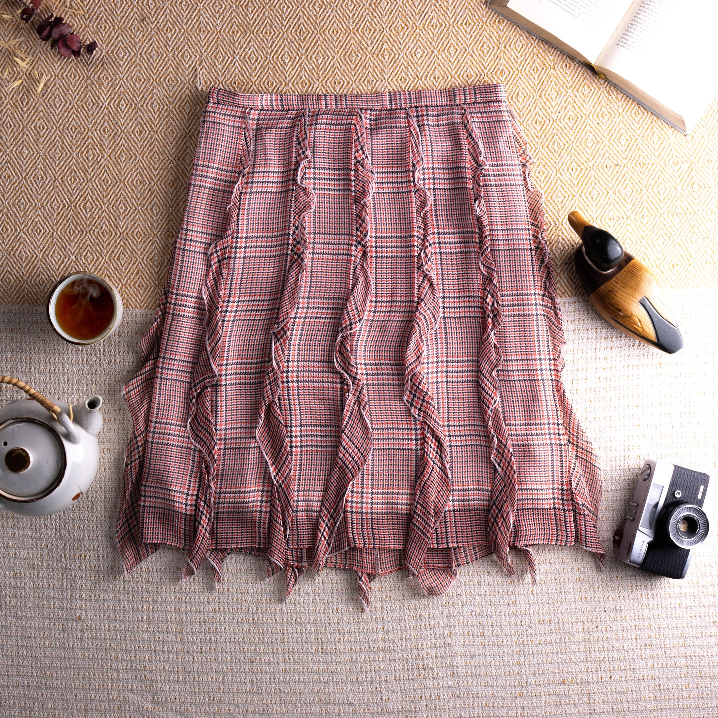 view back Vintage Cacharel Y2K Silk Ruffled Houndstooth Plaid Midi Skirt – blush pink, green and white houndstooth check silk, high waist, five vertical ruffle seam panels creating deconstructed avant-garde silhouette, raw fringe hem, A-line midi length, flat lay editorial shot