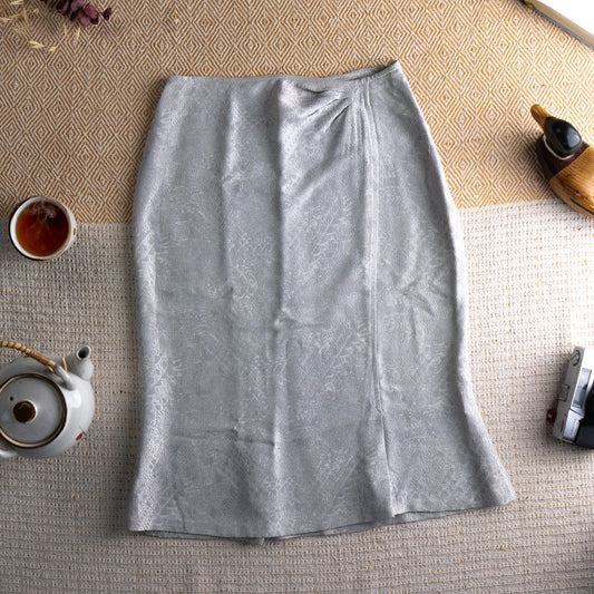 Christian Lacroix Bazar 90s Silver Jacquard Pencil Skirt – pale silver-grey tonal floral jacquard fabric with subtle shimmer, high waist with front pleat detail, straight pencil midi silhouette with back kick pleat, Made in France, mint condition collector piece, flat lay editorial shot