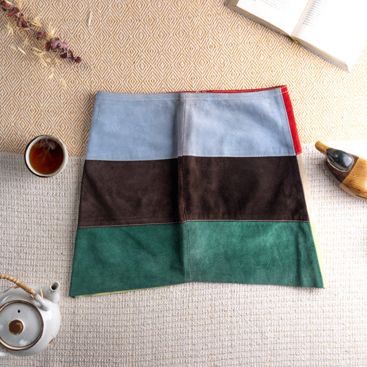 Vintage Miss Sixty Y2K Suede Patchwork Mini Skirt – genuine leather suede horizontal colour block panels in powder blue, dark chocolate brown and forest green with red side trim, contrast white topstitching, low waist, straight mini silhouette, boho festival 90s aesthetic, flat lay editorial shot