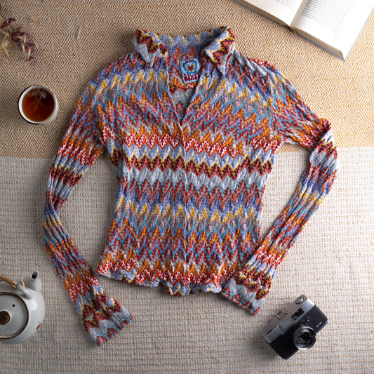 Vintage Miss Sixty 90s Multicolour Zig Zag Knit Button-Up Cardigan – 100% cotton open-weave chevron knit in lavender blue, burnt orange, red, yellow and teal, pointed collar, silver snap button-front, long sleeves with button cuffs, Miss Sixty butterfly logo patch at chest, fitted boho archive silhouette, flat lay editorial shot