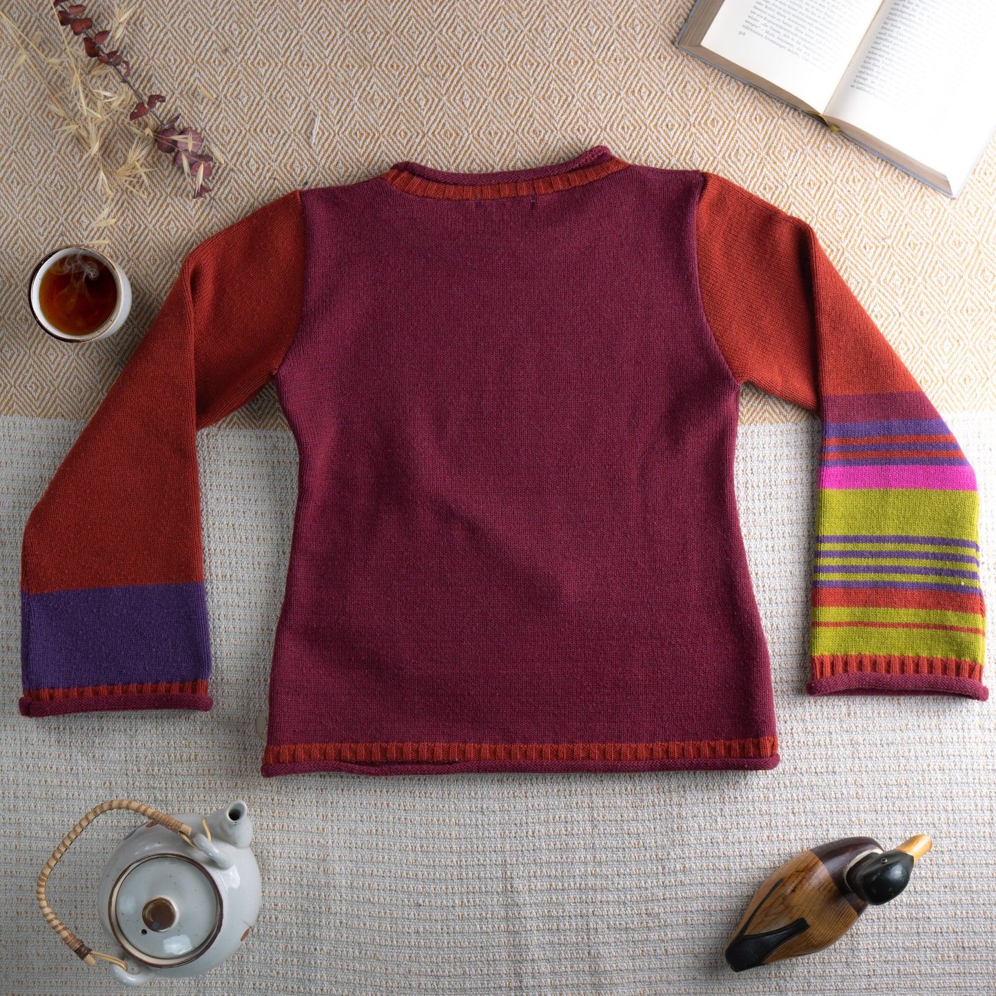 back view Archival Cop Copine Paris Y2K "RHIN" Colorblock Knit Sweater – burgundy body with rust orange raglan sleeves, multicolour stripe cuffs in yellow, pink, purple and blue, contrasting orange picot trim at neckline and hem, single front kangaroo pocket, avant-garde Made in France, flat lay editorial shot