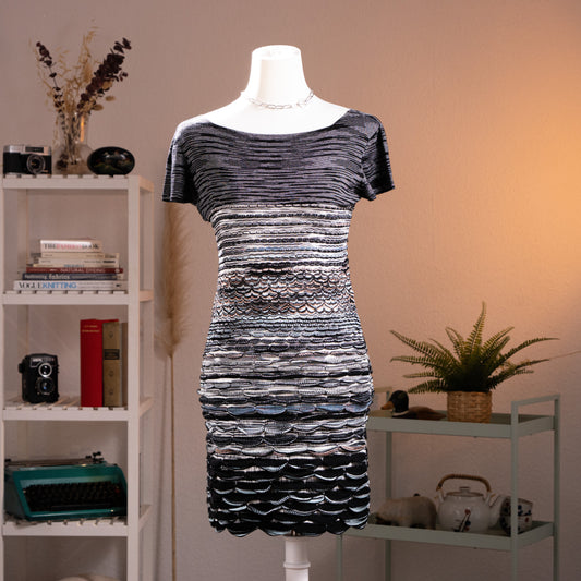 Archival Missoni Orange Label 90s 3D Scalloped Knit Mini Dress – black and silver metallic knit, wide scoop neckline, short sleeves, horizontal stripe bodice transitioning into dramatic 3D raised scallop shell texture panels at waist and skirt, body-con silhouette, textile sculpture Angela Missoni era, product shot on dress form