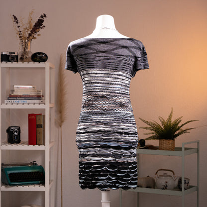 back view Archival Missoni Orange Label 90s 3D Scalloped Knit Mini Dress – black and silver metallic knit, wide scoop neckline, short sleeves, horizontal stripe bodice transitioning into dramatic 3D raised scallop shell texture panels at waist and skirt, body-con silhouette, textile sculpture Angela Missoni era, product shot on dress form