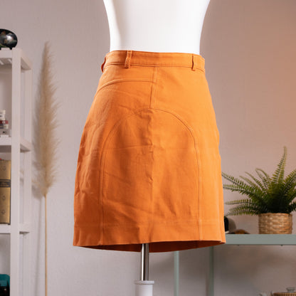 back view Archival Gucci by Tom Ford 1999 Orange Ottoman Utility Mini Skirt  sample prototype atelier– saturated carrot orange structured ottoman fabric, low rise with single gold button and belt loops, asymmetric curved seam panelling at front, dual zip pocket detail at waistband, clean A-line mini silhouette, atelier sample IT 42, product shot on dress form