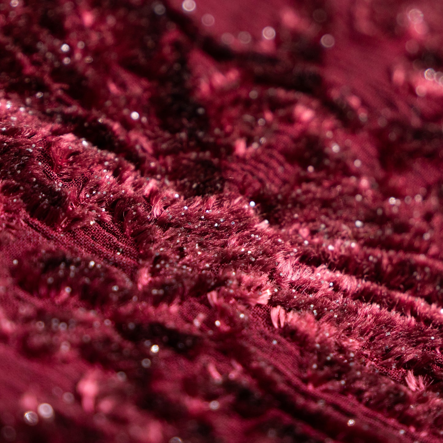Macro textile detail of Lolita Lempicka devore velvet fabric, showing microscopic silver Lurex threads interwoven into the burgundy pile, crystalline micro-sequins, and texturized silk-jacquard chiffon matrix.