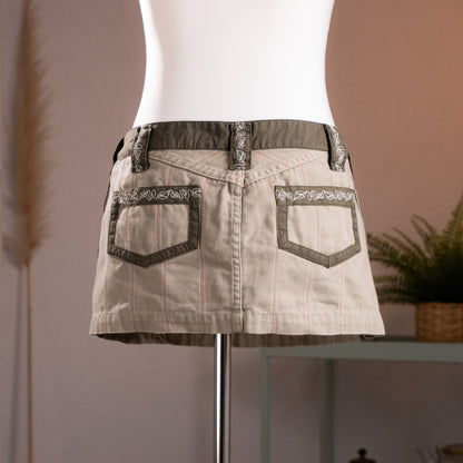 Rear view of the archival Diesel utility mini skirt, showing the deep V-shaped yoke, twin spade patch pockets with olive twill framing, and geometric cyber-jacquard webbing on belt loops.
