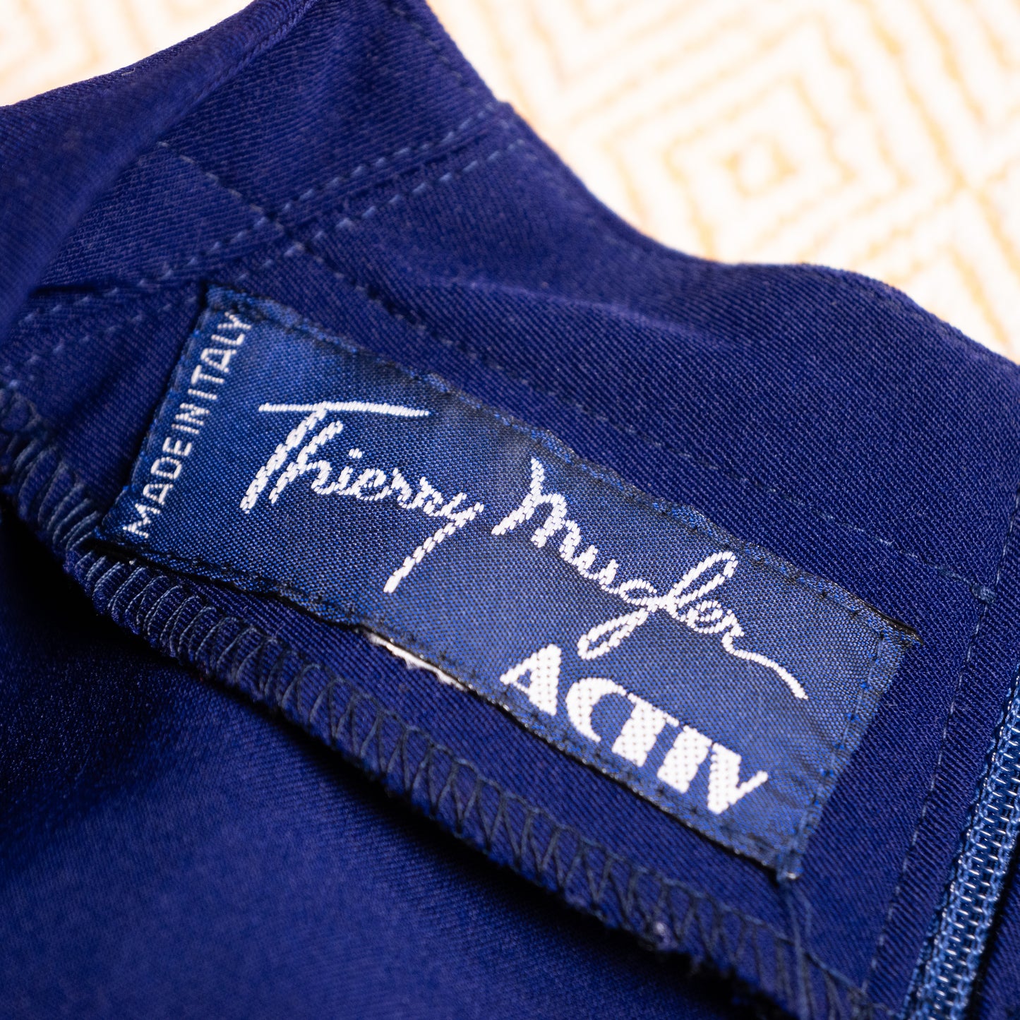Rear close-up of the historical Thierry Mugler Activ dress, revealing a color-matched invisibly set zipper running through the architectural standing collar. Flawless fabric matrix and precise industrial finish by Time Srl.


