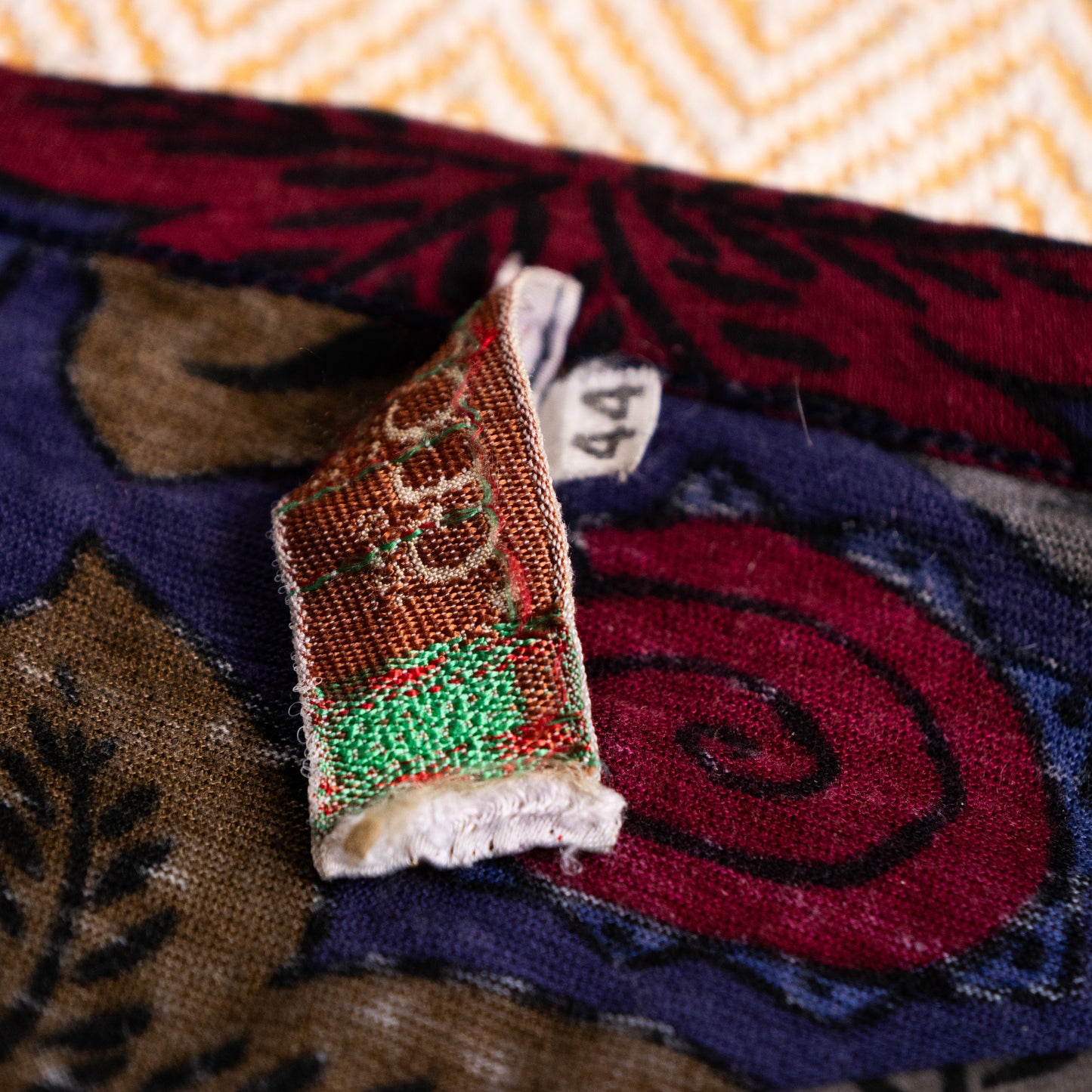 Reverse side of a vintage Gucci woven neck tag displaying the mirrored Jacquard weave structure of the threads.