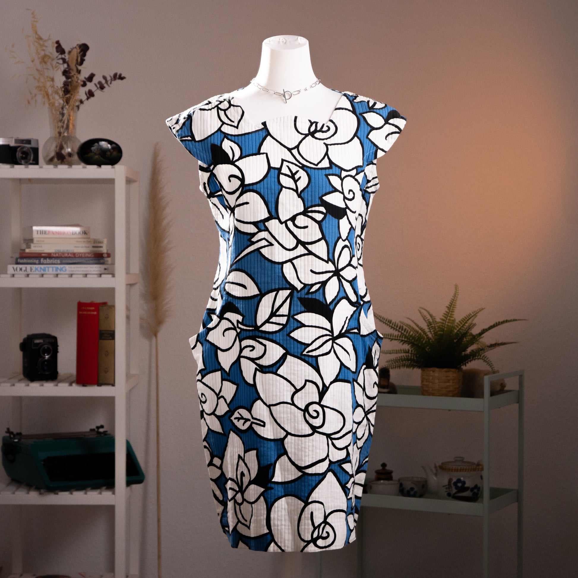 Front view of authentic vintage late 1980s Courreges pleated floral shift dress in electric blue and white on a mannequin highlighting signature hip patch pockets