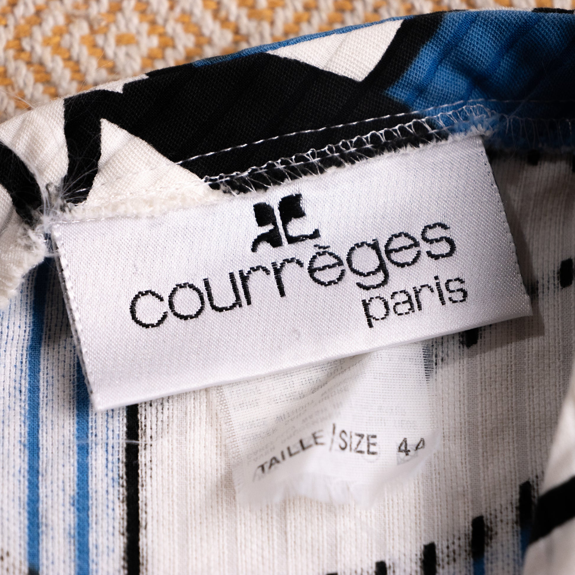 Close-up of authentic vintage Courrèges Paris woven neck label showing the iconic AC logo and attached Taille Size 44 tag.