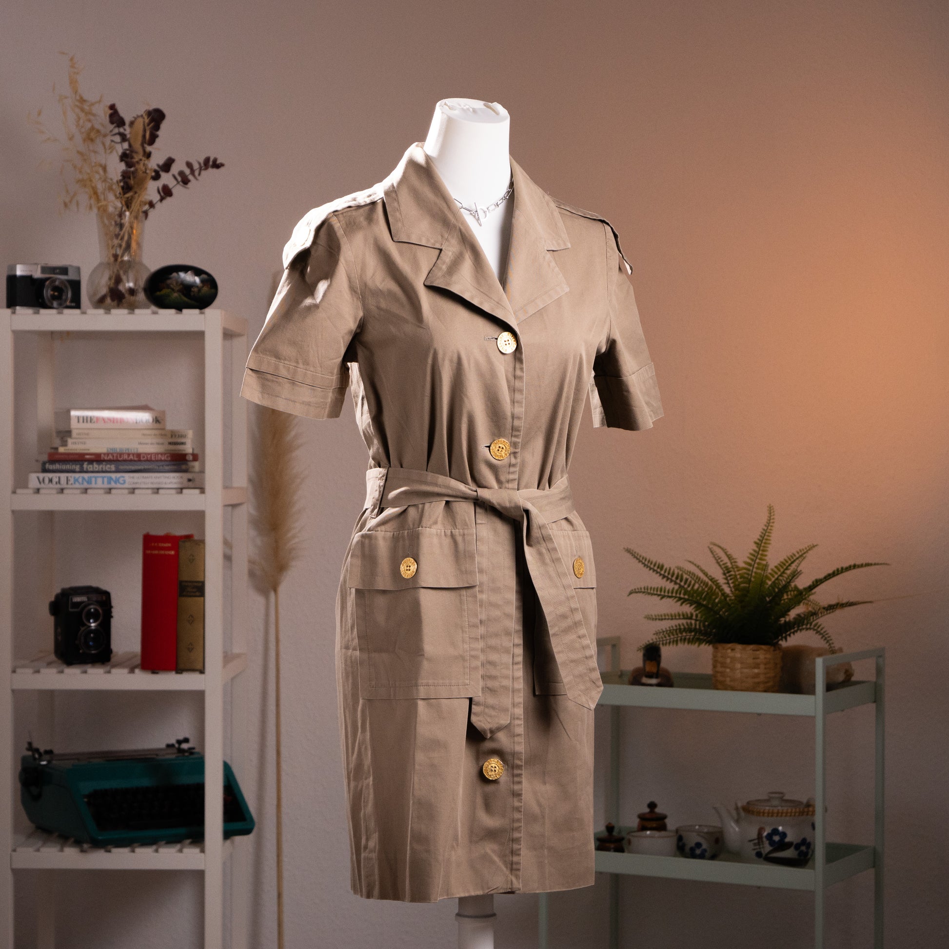 Front three-quarter view of an archival Boutiques Givenchy khaki cotton safari trench dress from the late 1980s on a museum mannequin.