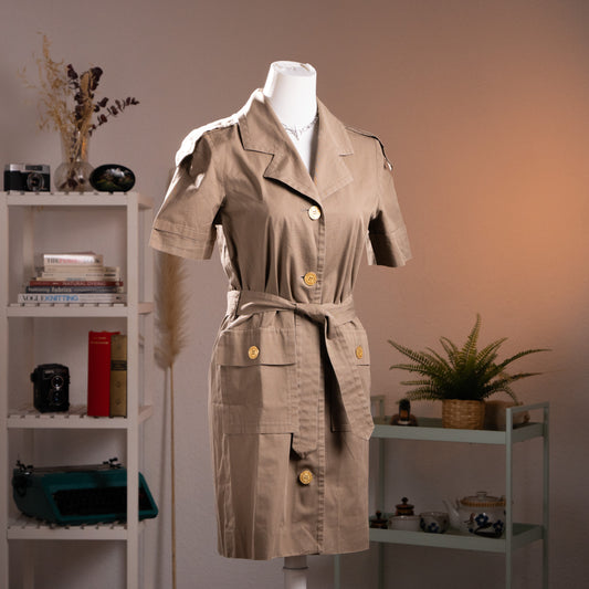 Front three-quarter view of an archival Boutiques Givenchy khaki cotton safari trench dress from the late 1980s on a museum mannequin.