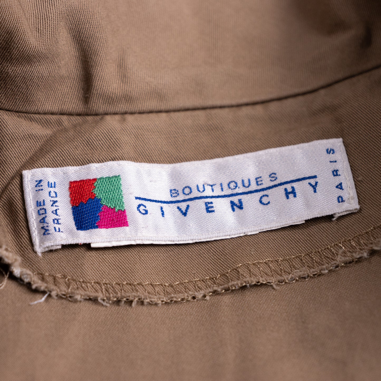 Close-up of the woven white Boutiques Givenchy Paris main label featuring the historic colorful four-quadrant logo.