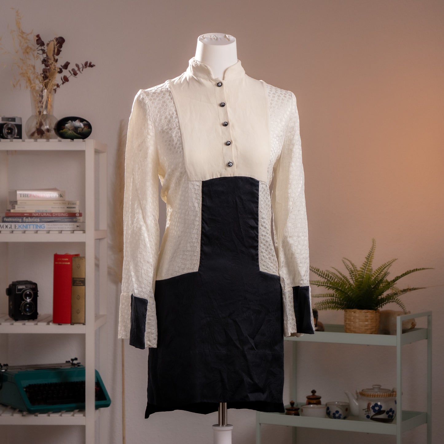 Front view of an archival Alexander McQueen ivory piqué and black silk runway dress from Fall Winter 2014 on a museum mannequin.
