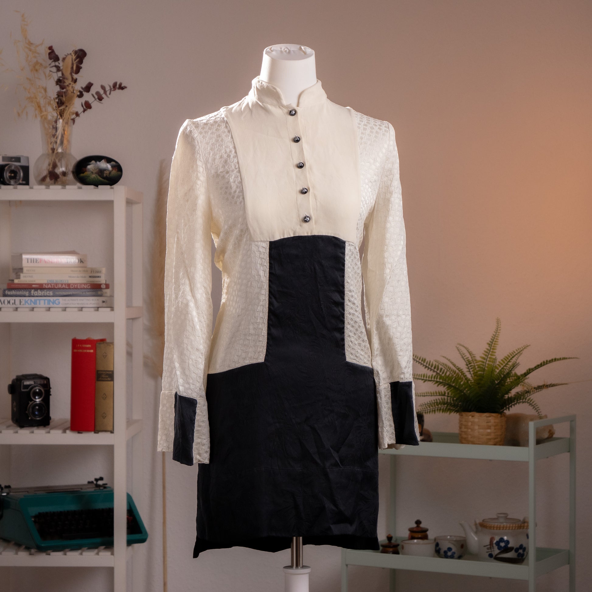 Front view of an archival Alexander McQueen ivory piqué and black silk runway dress from Fall Winter 2014 on a museum mannequin.