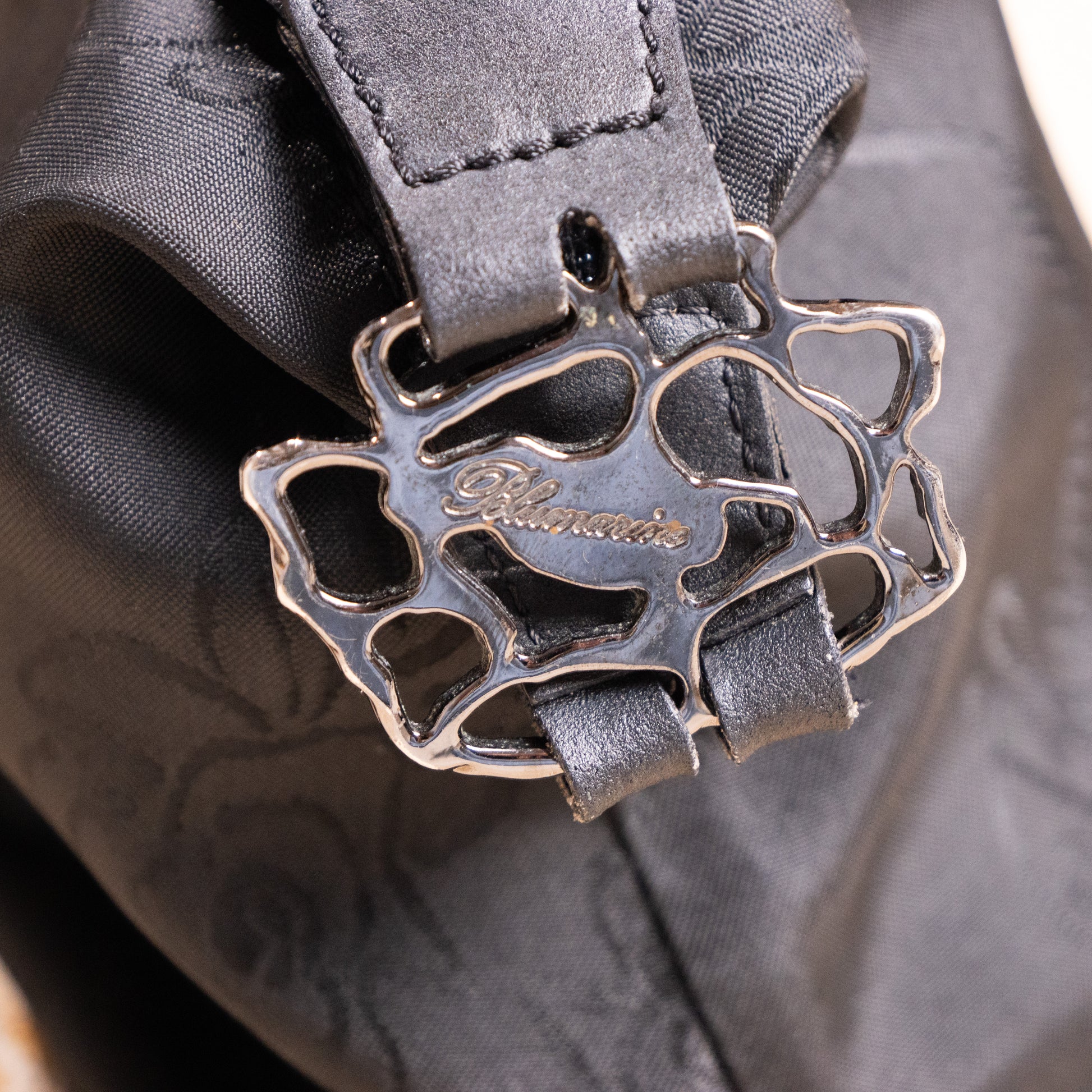 Close-up of sculptural silver-tone rose-vine metal buckle with engraved Blumarine logo on the archival deadstock baguette bag.