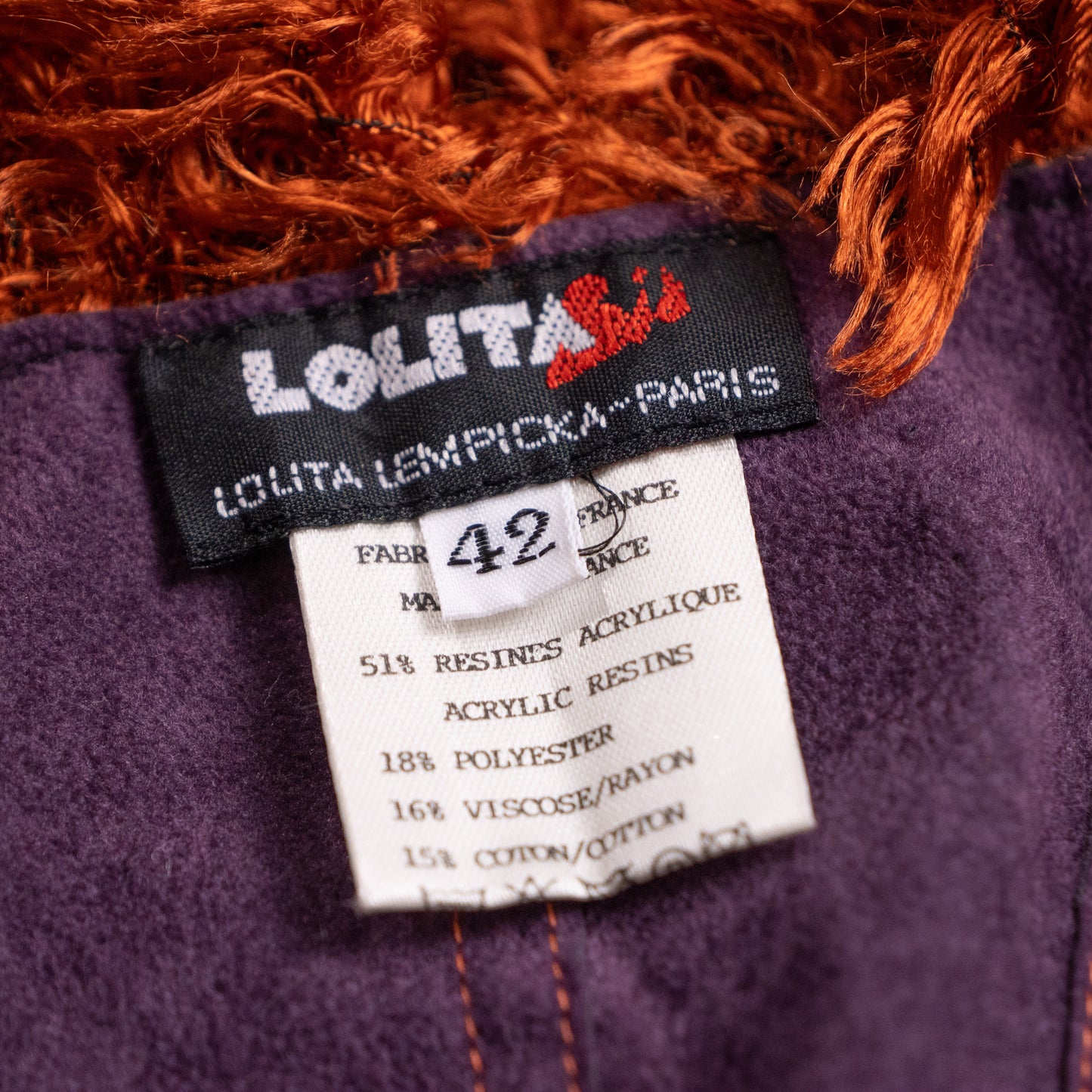 Close-up interior shot of the woven black Lolita Lempicka Paris label with red leaf motif and care instructions inside the archival fringe corset.