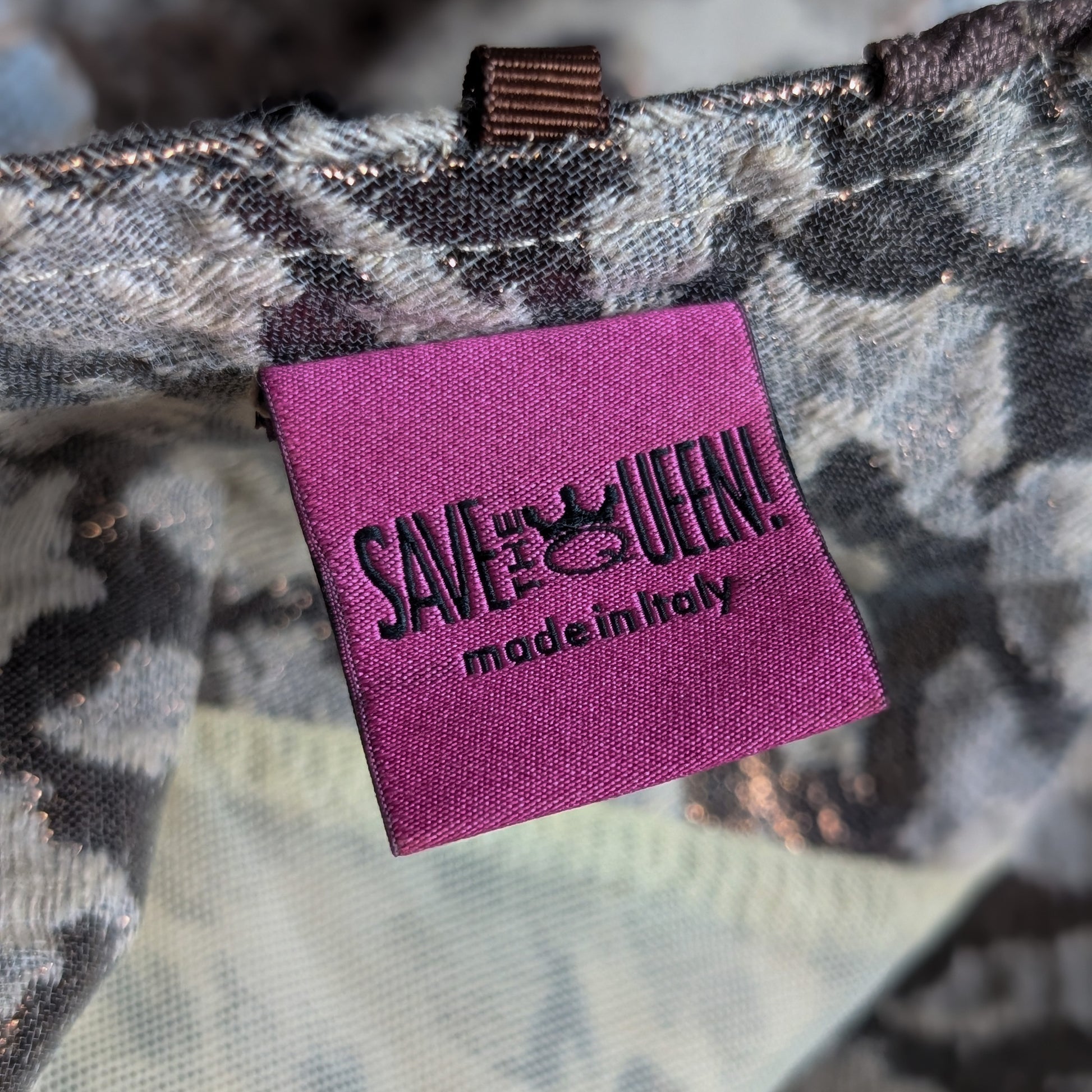 Purple tag with 'SAVE A QUEEN! made in Italy' text on a camouflage .background Save The Queen Archival Y2K Patchwork Midi Dress – ivory and grey mixed-media construction combining snake-print silk, diamond-weave linen, crochet lace and satin panels, asymmetric centre-front placket with large dark resin button closures, scoop neckline, sleeveless, ivory satin hem band with floral embroidery and fringe trim, art-to-wear, Marco Fantini Firenze, product shot on dress form